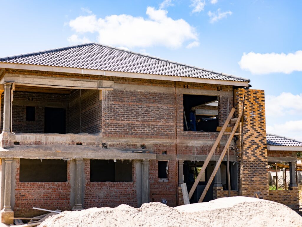 Concerned homeowner stands inside a house under construction, looking at an unfinished wall with exposed insulation, repre...